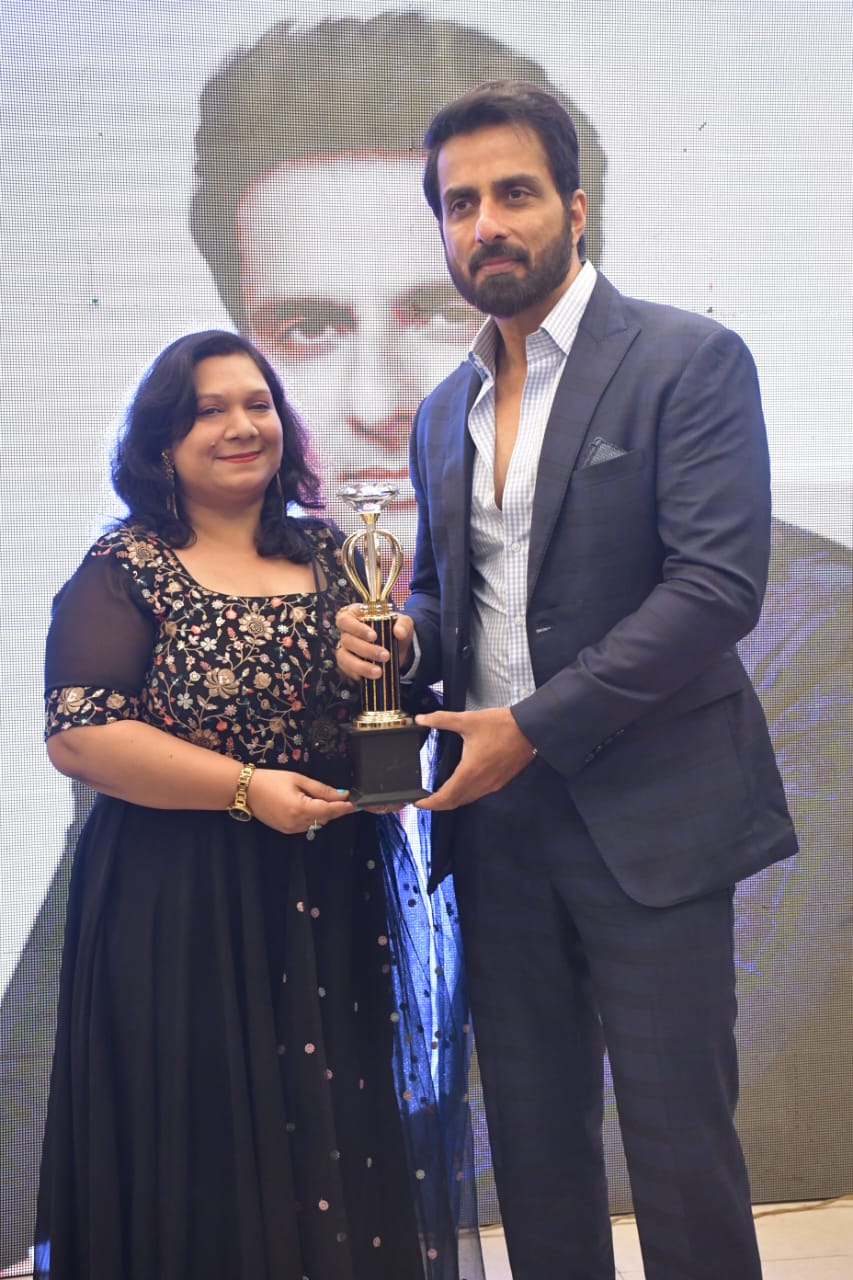 Dr. Aradhana Bhatnagar receiving an award trophy from actor Sonu Sood at an awards ceremony